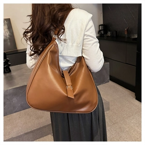 Macro detail of brown leather tote bag with elegant gold buckle and soft pleat texture