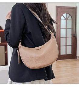 Detail of khaki hobo bag with wide woven strap and litchi grain leather texture