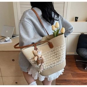 Detail of woven straw tote bag featuring contrast colors and teddy bear charm