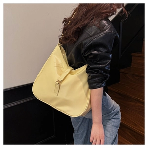 Side view of large light yellow hobo tote bag with vertical strap and metal buckle