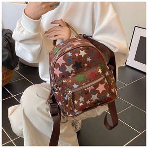 Close-up of mini brown canvas backpack with star embroidery held by a model