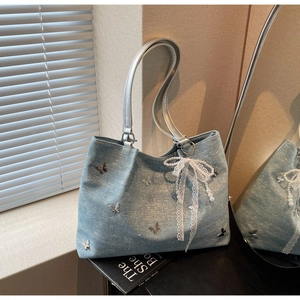 Detailed shot of blue denim tote bag with silver butterfly charms and pearl lace bow