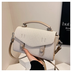 Close-up of textured fabric crossbody bag with leather flap and cylindrical buckle