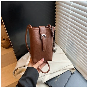 Close-up of brown litchi pattern leather mini phone bag with silver buckle and knot strap