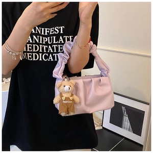 Detail of light purple pleated shoulder bag with cute teddy bear charm accessory