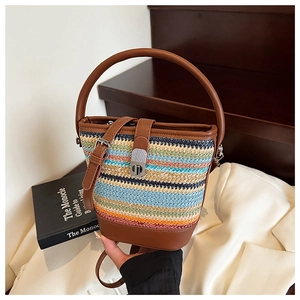 Detail of colorful woven straw bucket bag featuring brown leather trim and metal twist lock