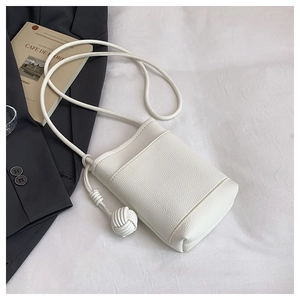 Detail of white mini crossbody bag with litchi texture and braided knot ball decoration