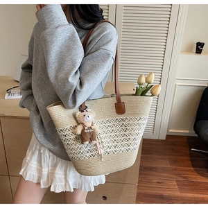 Detail of woven straw tote bag featuring contrast mesh texture and teddy bear charm