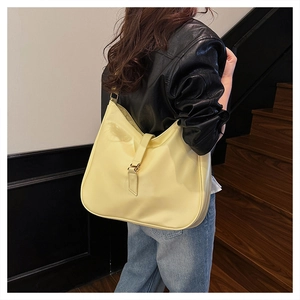 Side view of large light yellow hobo tote bag worn by model on a wooden staircase