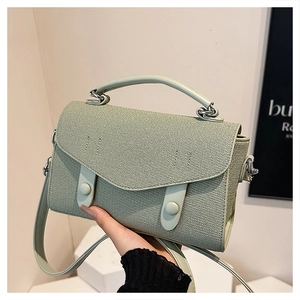 Detail showing mint green woven texture and smooth leather handle on a chic crossbody bag