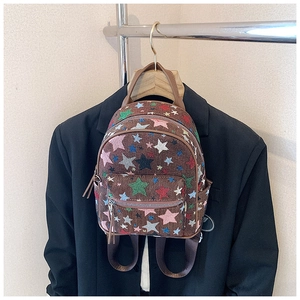 Detailed view of woven star patterns and leather zip pullers on a brown mini backpack