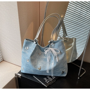 Detail of light blue denim tote with silver butterfly charms and lace pearl pendant