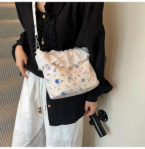 Floral crossbody bag detail with white lace edges and purple flower pattern on canvas