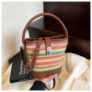 Detail of colorful rainbow straw bucket bag featuring brown leather trim and silver clasp