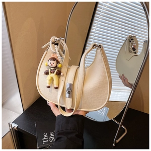 Close-up of beige crescent moon bag with textured leather and decorative pearl chain