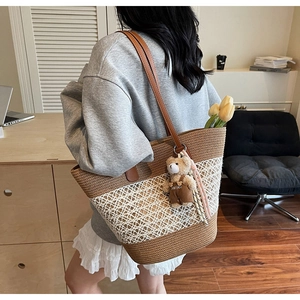 Detail of woven straw tote bag with floral lace panels and cute bear charm accessory