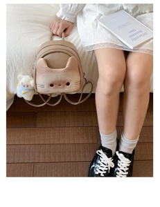 Detail of cute cat face texture on mini backpack with plush bear charm and leather finish