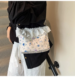 Detailed view of floral pattern and white lace embroidery on a soft cotton shoulder bag