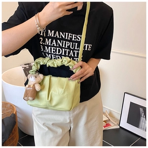 Detail of light green ruched cloud bag featuring a cute teddy bear charm and ruffled handle