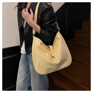 Detail of light yellow hobo tote bag featuring adjustable buckle and smooth PU leather