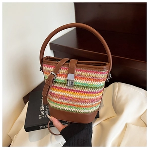 Detailed view of colorful woven straw bucket bag with brown leather trim and metal lock