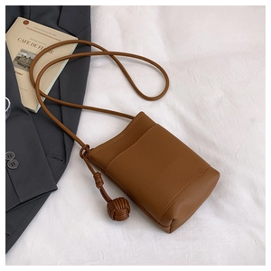 Detail of a brown lychee pattern leather mini crossbody bag on white linen
