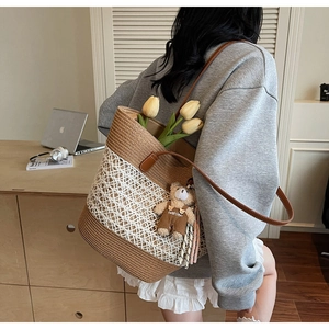 Detail of woven straw tote bag with white mesh design and brown leather straps
