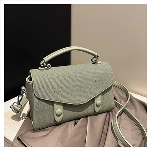 Detail of mint green crossbody bag featuring woven texture flap and silver metal fasteners
