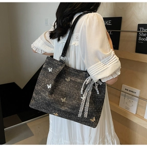 Detail view of a large dark grey glitter tote bag with 3D metal butterfly and pearl lace bow