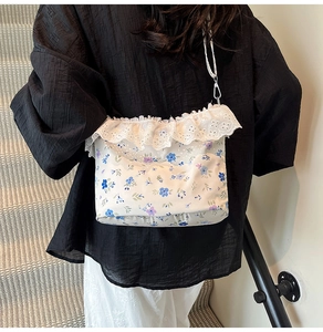 Close-up of floral crossbody bag featuring delicate white lace trim and blue flower patterns
