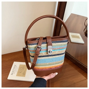 Detail of colorful woven bucket bag featuring brown leather strap and silver twist-lock closure
