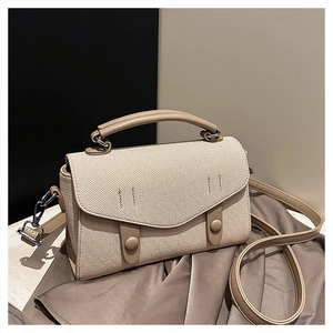 Detail of minimalist cream woven canvas crossbody bag with leather trim and gold buckles
