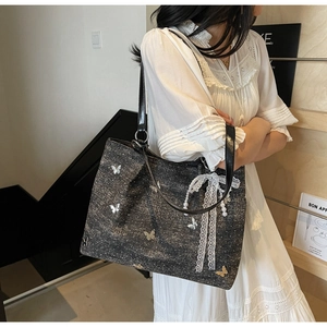 Detail of black sequin tote bag with silver butterflies and pearl lace bow charm