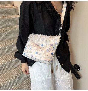 Close-up of floral crossbody bag with white lace trim and blue purple flower pattern