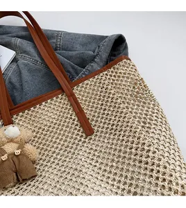 Détail du sac fourre-tout en paille tissée avec lanières en cuir et breloque ours