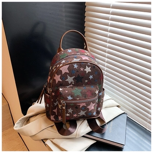Detail of mini fabric backpack featuring colorful star patterns and brown leather accents