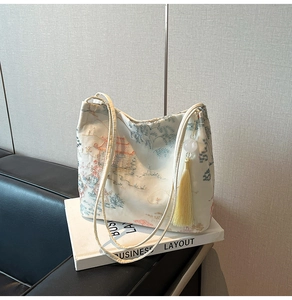 Detail view of Chinese style embroidery with tassel on cream white crossbody bucket bag