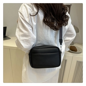 Detail of black litchi texture PU crossbody bag with striped wide fabric strap