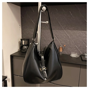 Detail of a large black hobo tote bag featuring a subtle matte finish and gold metal clasp