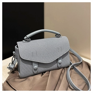 Detail of light blue crossbody bag featuring twill texture and silver metal hardware