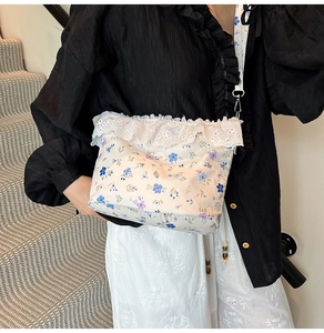 Detail of floral crossbody bag with white lace trim and drawstring strap on model