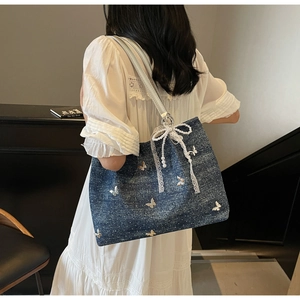 Detail of blue denim tote bag with white lace pearl bow and butterfly prints