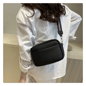 Detail view of black litchi pattern PU leather crossbody bag with wide striped strap