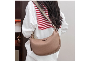 Detail of brown lychee grain leather crescent bag with patterned wide woven strap