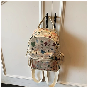 Detailed close-up of a white canvas backpack featuring vibrant colorful star embroidery