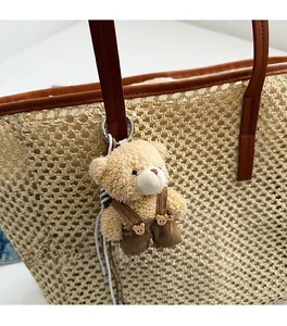 Détail d'un ours en peluche avec salopette en velours côtelé sur un sac cabas en paille