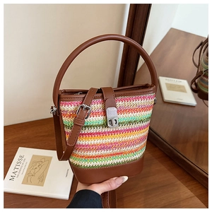 Detail of colorful rainbow woven straw bucket bag with brown leather handles and silver clasp
