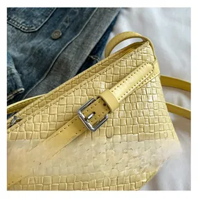 Dettaglio della trama in pelle intrecciata giallo chiaro e fibbia metallica della borsa