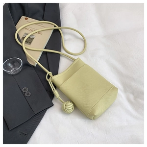 Detail view of lime green mini crossbody bucket bag with lychee leather texture