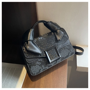 Détail d'un sac à main noir à texture serpent avec boucle carrée et poignée nouée